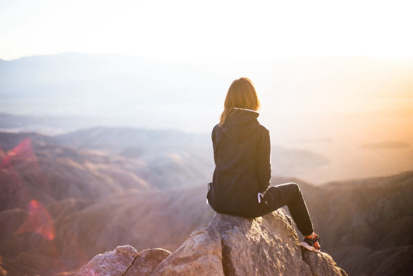 Person auf einem Felsen mit weitem Blick in die Landschaft